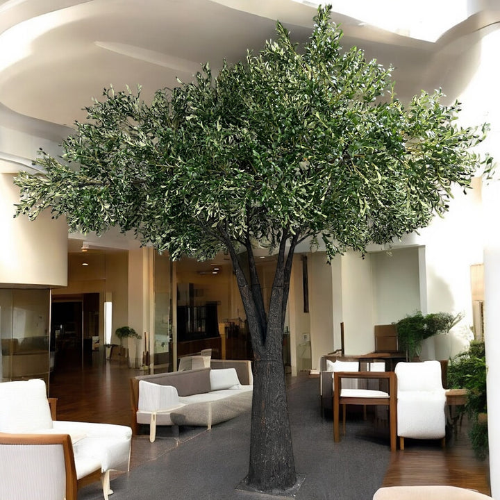 Large artificial olive tree in a modern indoor setting with furniture and decor.