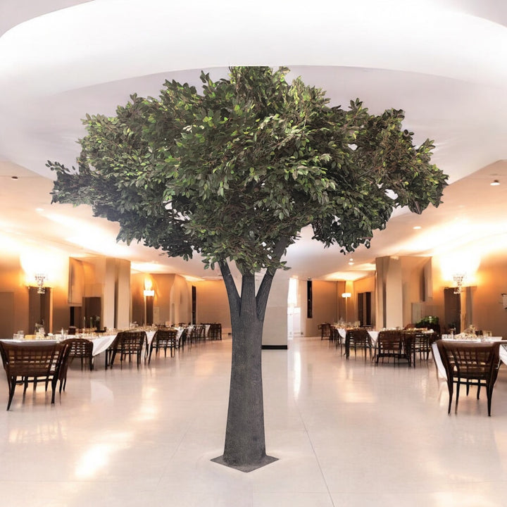 Large artificial ficus tree in a modern indoor setting with tables and chairs.