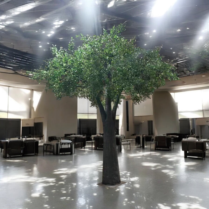 Large artificial olive tree in a modern indoor setting with chairs and tables.