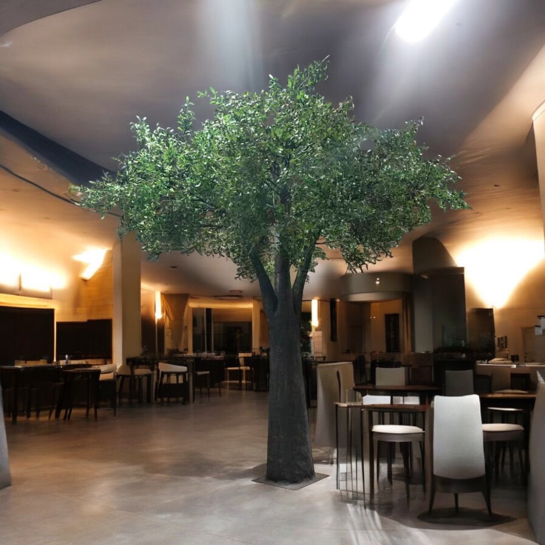 Large artificial olive tree in a modern indoor setting with tables and chairs.