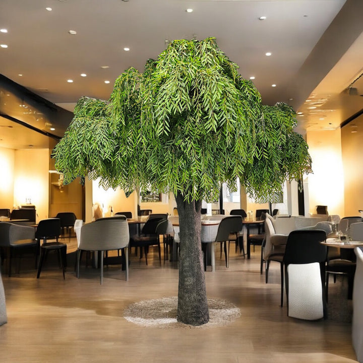 Large artificial willow tree in a modern indoor setting with chairs and tables.