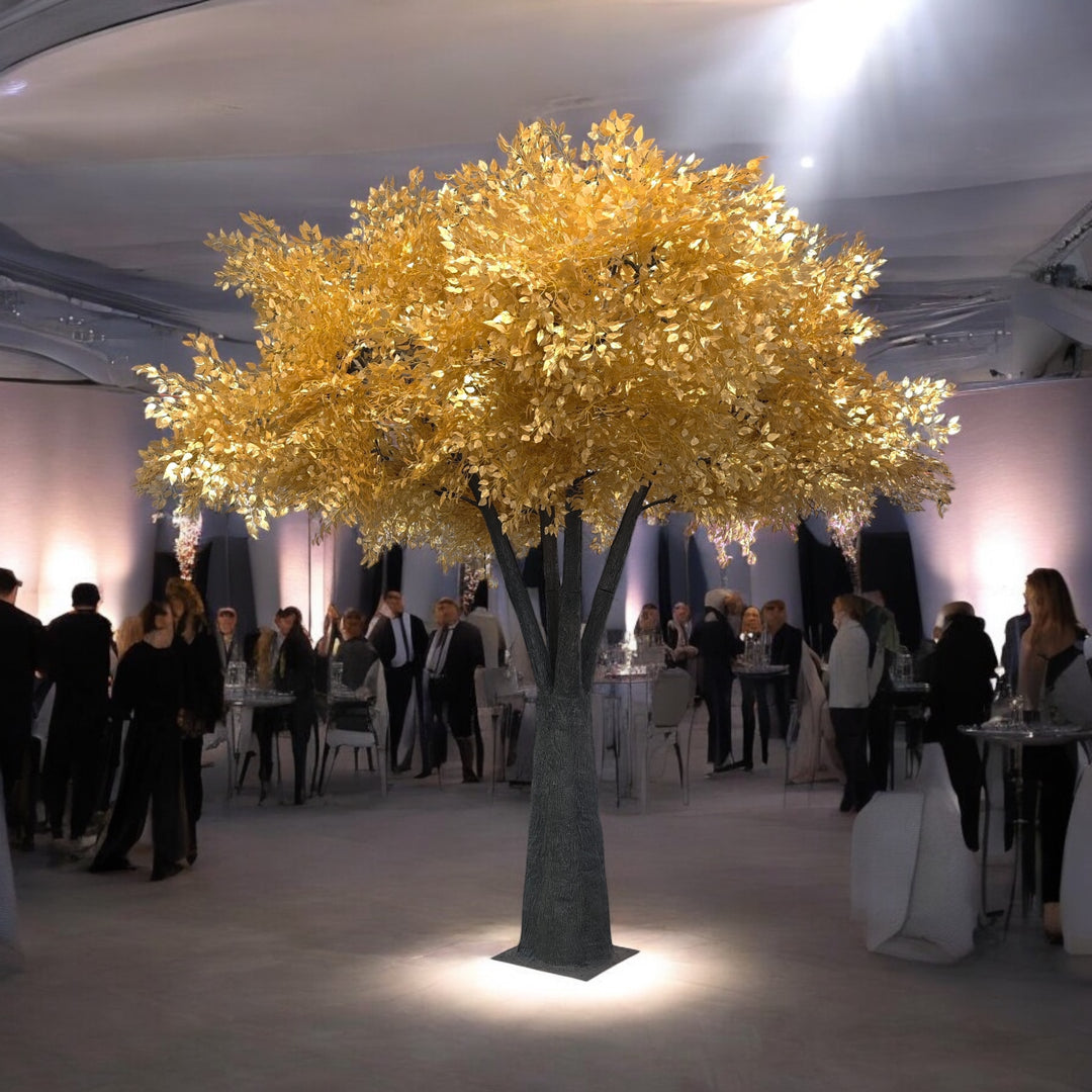 Decorative ficus tree with gold leaves in a room with people and tables.