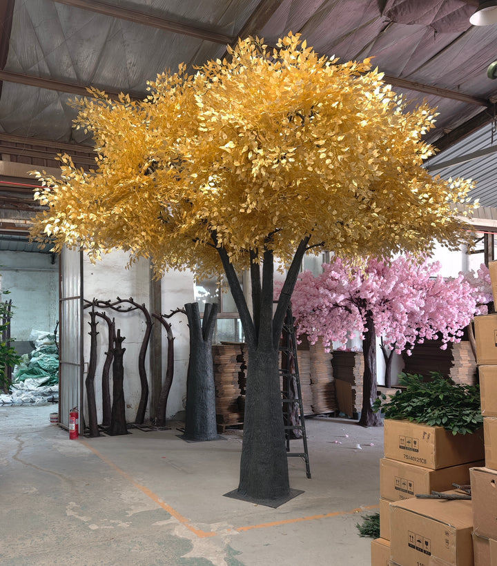 Large artificial ficus  tree with gold leaves in a warehouse setting