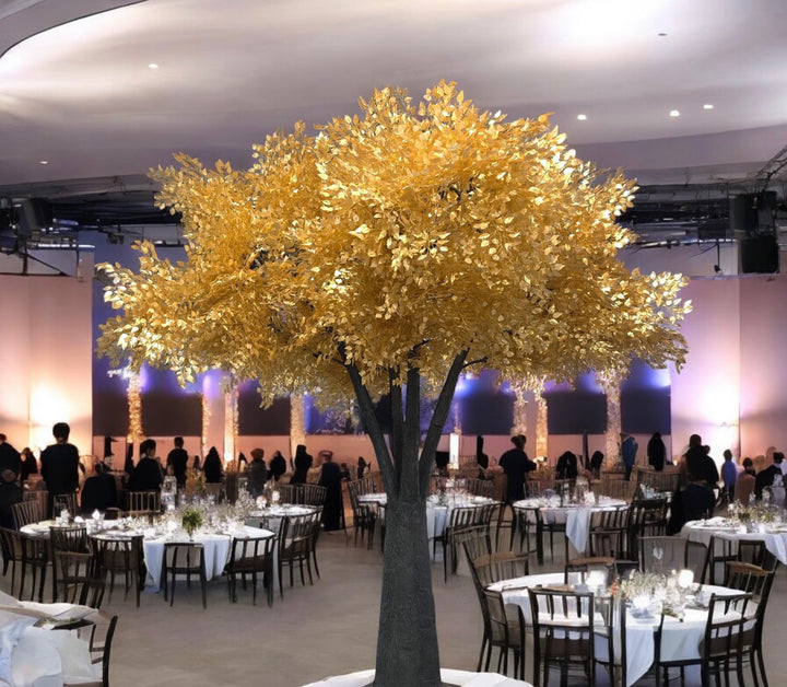 Decorative gold tree in a large indoor event space with tables and chairs.