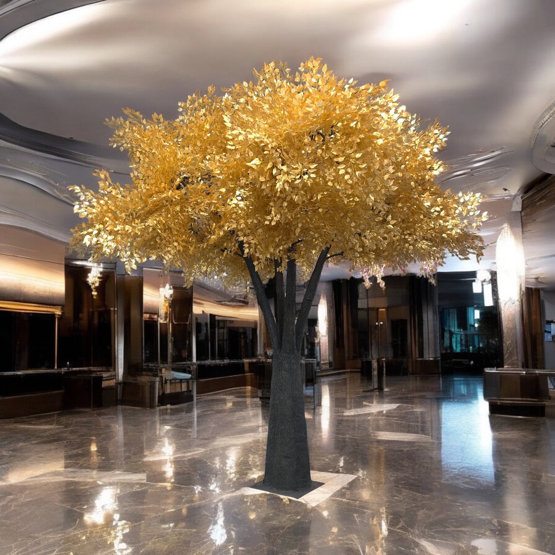 Decorative gold leaf ficus tree in a grand hallway with reflective floor and high ceilings.