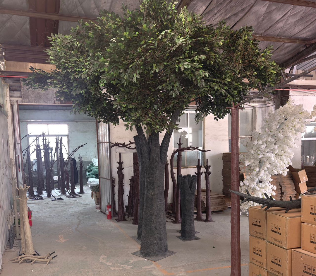 15ft artificial ficus tree standing in a high-ceiling warehouse showcasing dense foliage and natural vertical proportions.