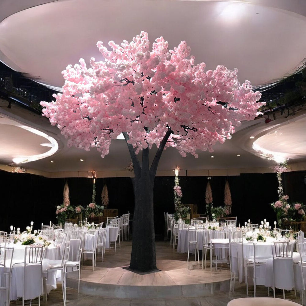 Decorative 15ft artificial pink cherry blossom tree in a banquet hall with tables and chairs.