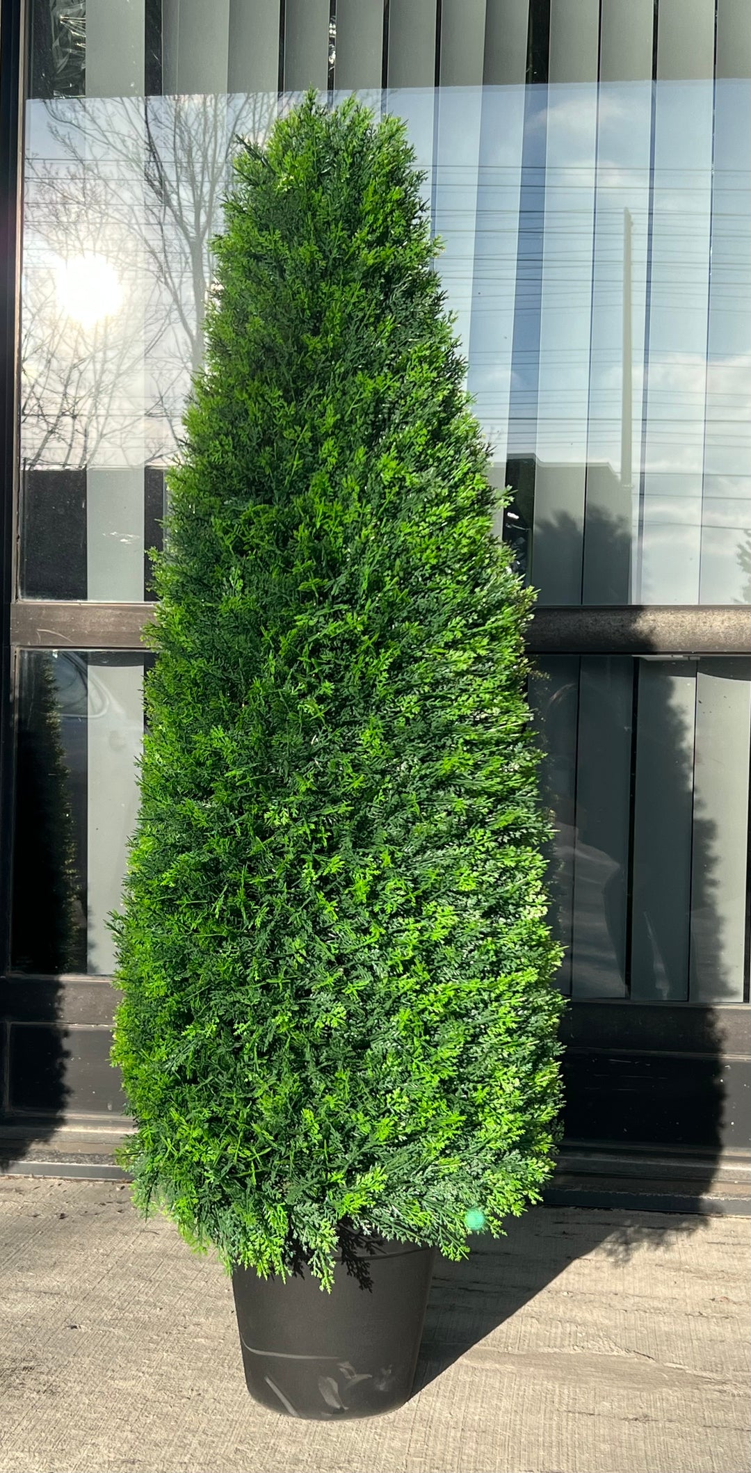 Artificial tall evergreen shrub in a black pot, ideal for enhancing outdoor spaces with its lush, realistic foliage.