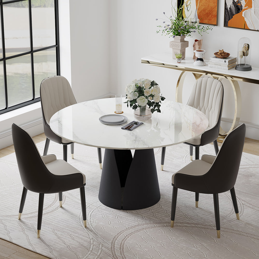 Elegant round dining table with a marble top in a modern dining room. The table is surrounded by stylish chairs with black and beige upholstery. A floral centerpiece adds a touch of sophistication, while a sleek console table and contemporary decor enhance the room's aesthetic. Large windows provide natural light, illuminating the chic interior design