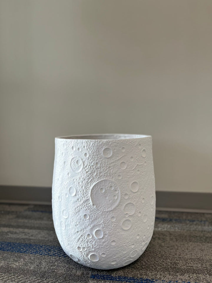 White planter with a crater-like textured design, displayed empty indoors on a carpeted floor against a neutral background. What is the weight of this planter when empty?