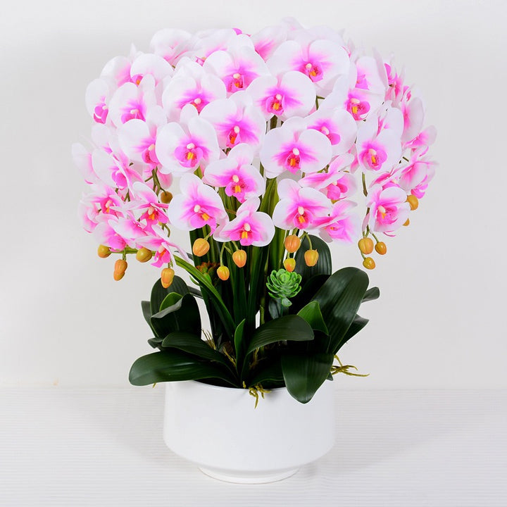 A beautiful artificial orchid arrangement in soft pink and white hues, set in a white ceramic pot with realistic green leaves and yellow buds. How do I maintain the freshness and appearance of artificial orchid flowers?