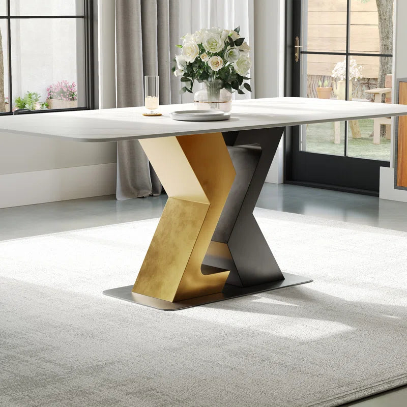 Close-up view of a modern dining table featuring a sleek white top and a striking gold and black geometric base, ideal for adding a contemporary touch to dining spaces