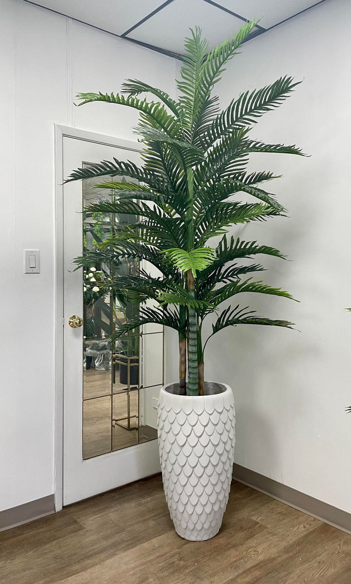 Realistic artificial palm tree in an elegant textured white planter, set in a modern office space with a mirrored door backdrop and wooden flooring.
