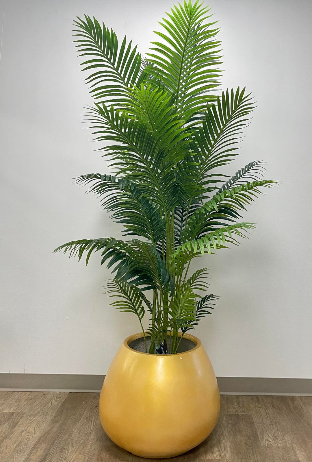 Artificial palm tree in a modern white pot, perfect for adding a tropical touch to indoor spaces with its lush green foliage.