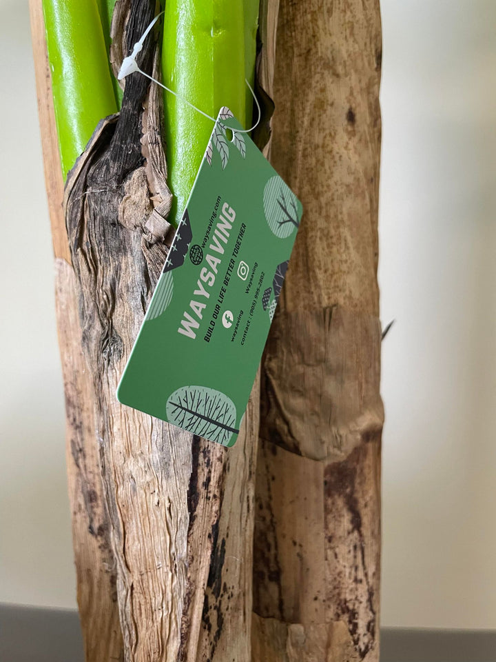 Close-up of an artificial banana plant trunk with a green tag labeled 'WAYSAVING,' highlighting the realistic texture and quality of the plant's materials