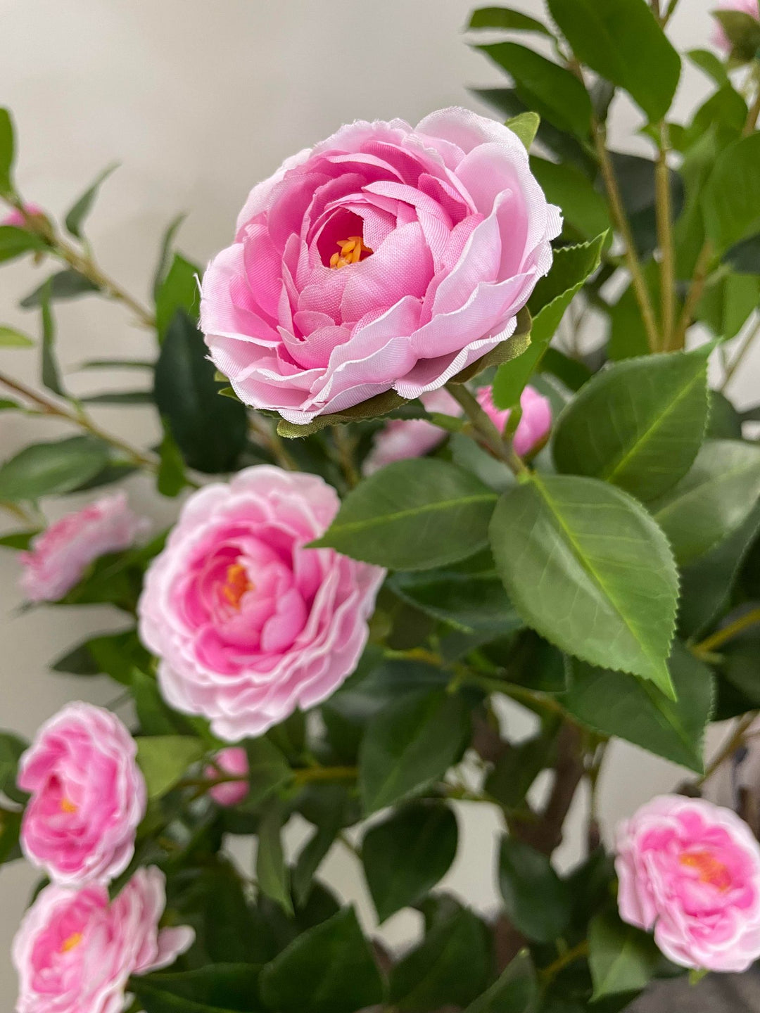 Artificial pink flowers with lush green leaves, perfect for brightening up any space with a realistic floral display for home or office décor.