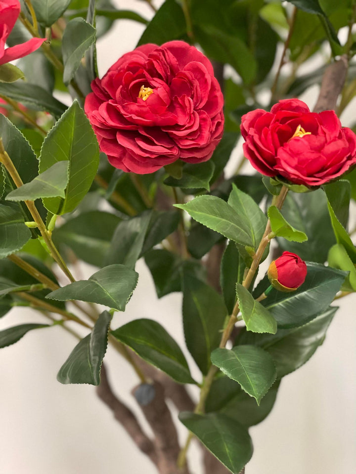 Close-up of artificial red flowers with green leaves, perfect for adding a realistic and vibrant touch to home or office decor.