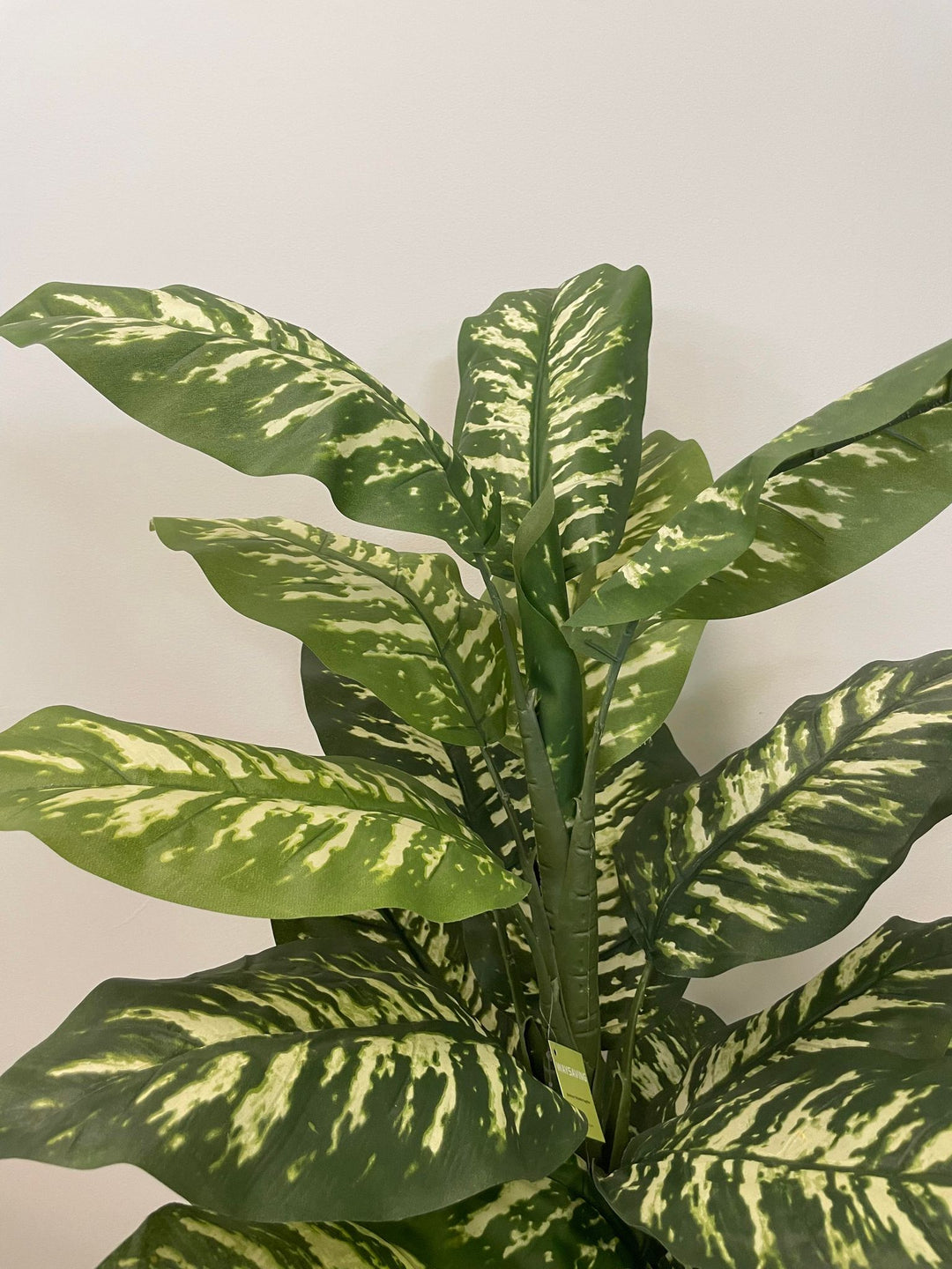 Close-up view of a vibrant artificial plant with variegated green leaves, ideal for adding a natural touch to indoor spaces.