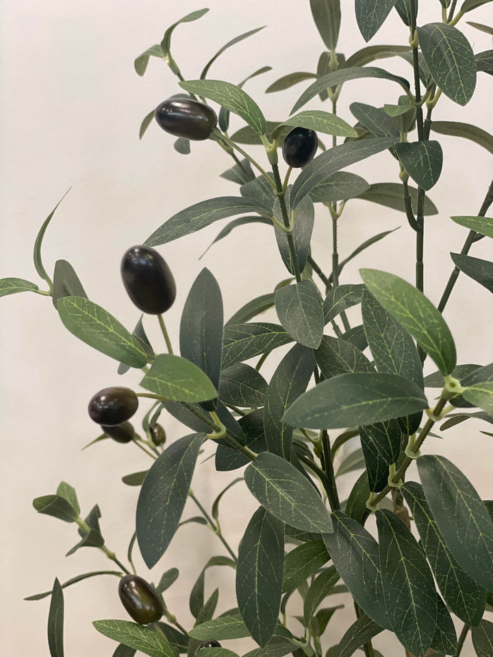 Close-up view of the artificial olive tree's leaves and small dark olives, showing the detailed texture and realistic design of the foliage against a neutral background.