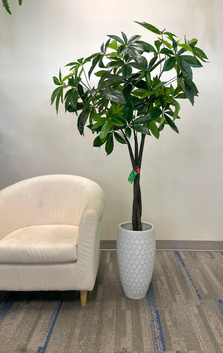 Artificial money tree with lush green leaves in a stylish white textured planter, placed beside a cozy white armchair in a modern indoor setting, perfect for enhancing office or home decor