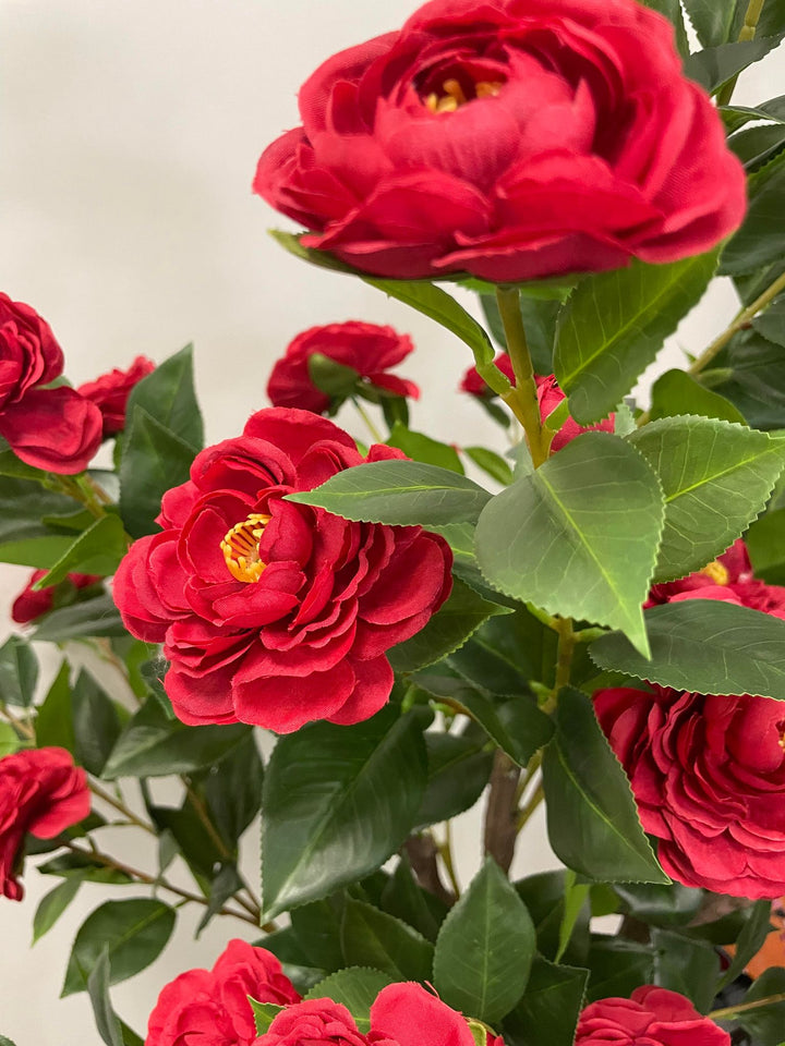 Close-up of artificial red flowers with green leaves, perfect for adding a realistic and vibrant touch to home or office decor.