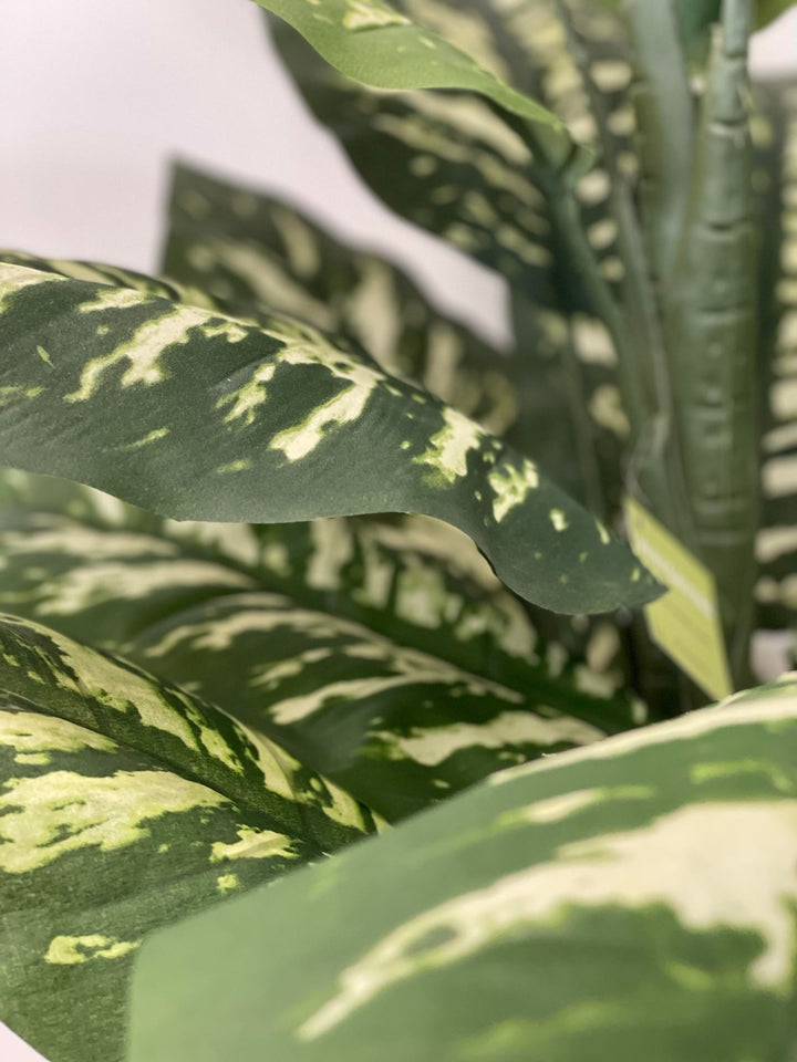 Close-up view of a vibrant artificial plant with variegated green leaves, ideal for adding a natural touch to indoor spaces.