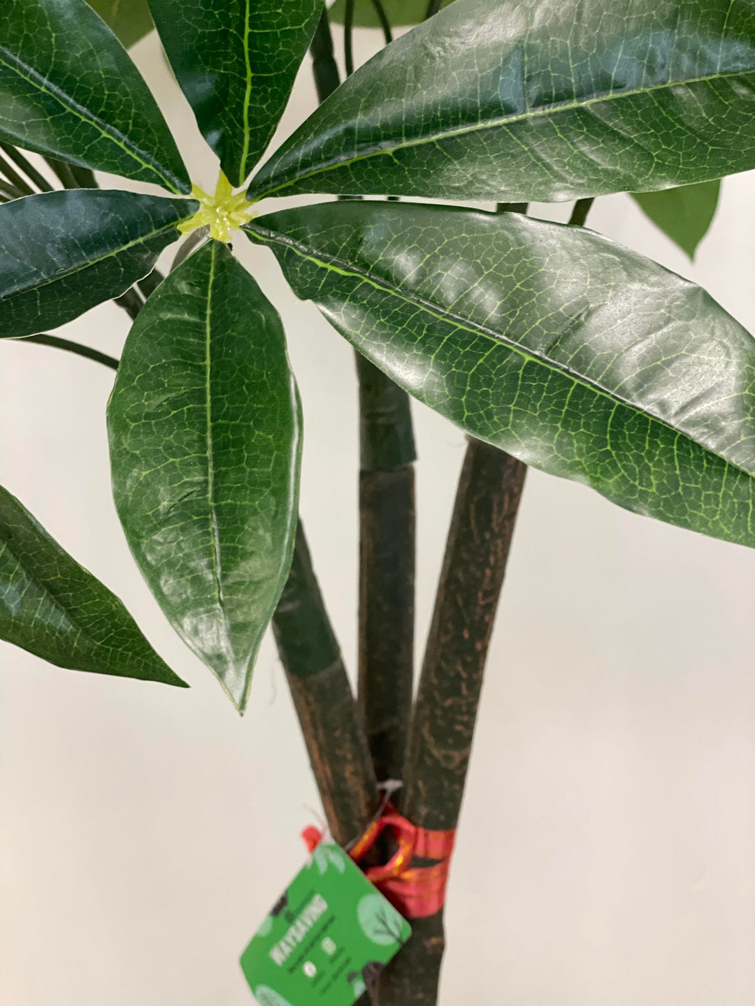 Detailed view of artificial money tree leaves against a textured trunk, highlighting the vibrant green foliage and lifelike appearance, ideal for indoor decor