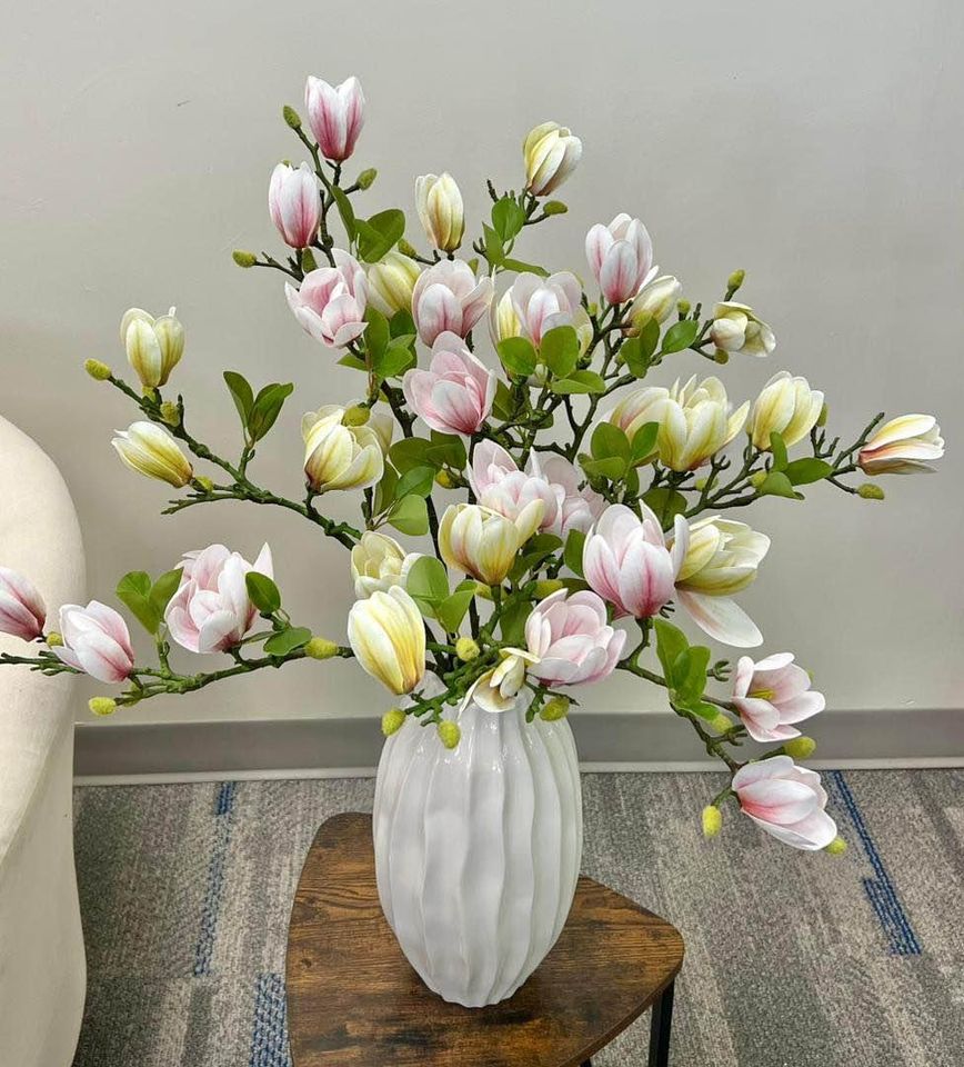 A beautiful arrangement of artificial magnolia flowers in soft pink and cream hues, displayed in a textured white vase. Frequently asked question: What are the best artificial flowers to use for home decor that offer a natural and fresh look?