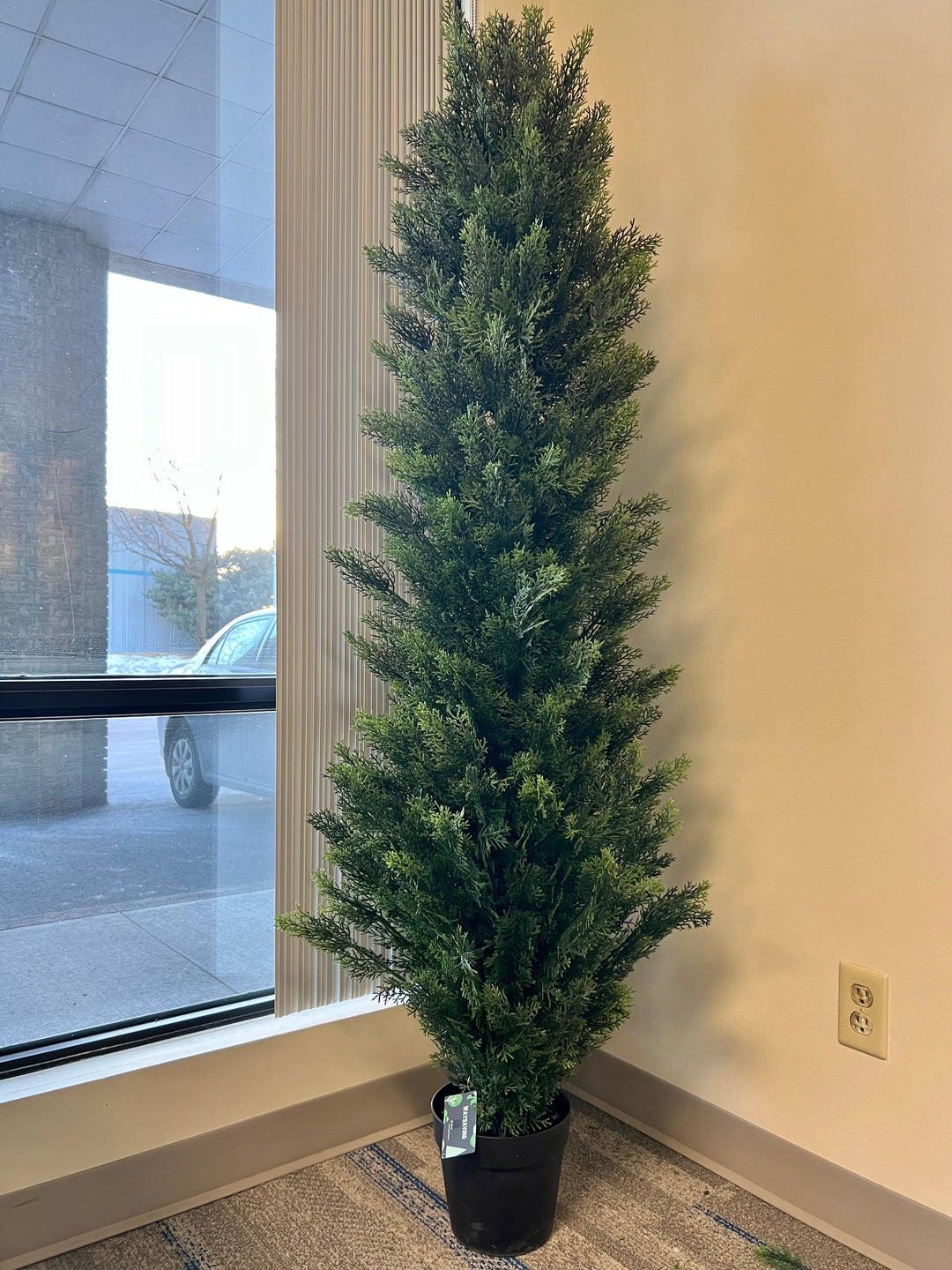 Artificial slim evergreen tree in a black pot, perfect for adding a touch of greenery to small indoor spaces like offices or living rooms.