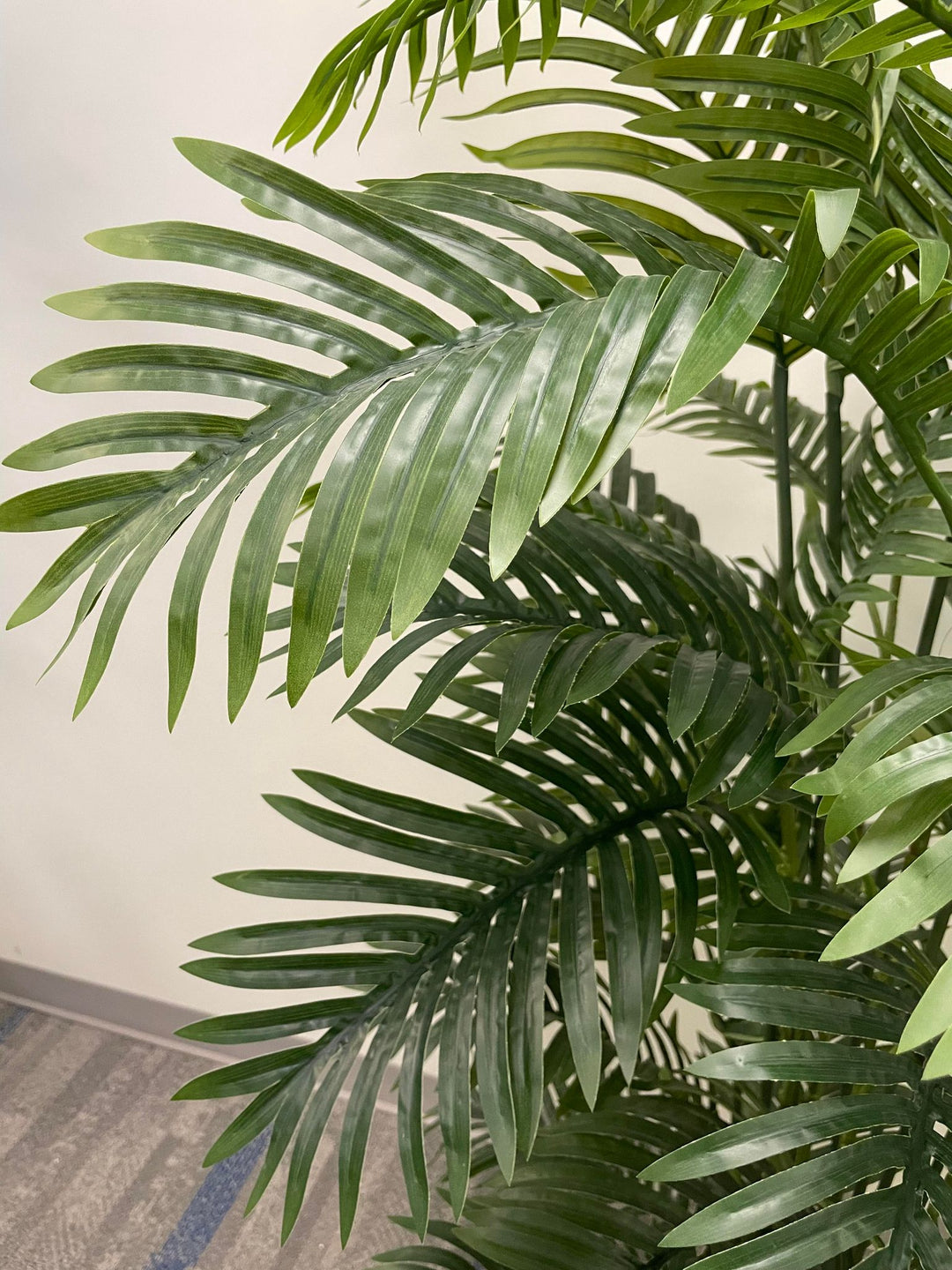 Close-up of artificial palm fronds, showcasing vibrant green leaves and realistic detailing, ideal for indoor decoration.