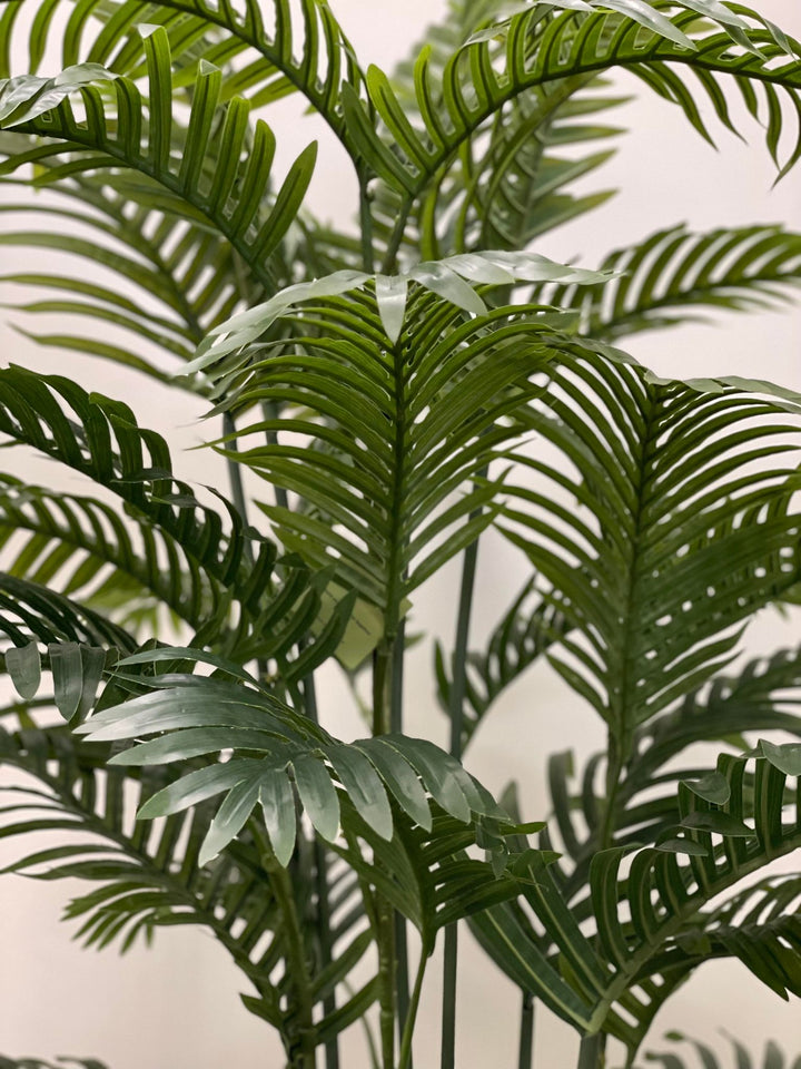 Close-up of artificial palm fronds, showcasing vibrant green leaves and realistic detailing, ideal for indoor decoration.