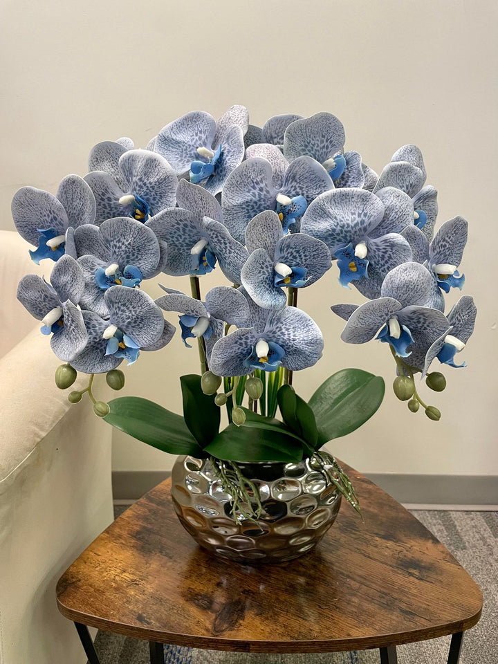 A stunning arrangement of artificial blue-speckled orchids in a metallic vase with glossy leaves. Frequently asked question: What are the best ways to clean artificial orchids without damaging their delicate appearance?
