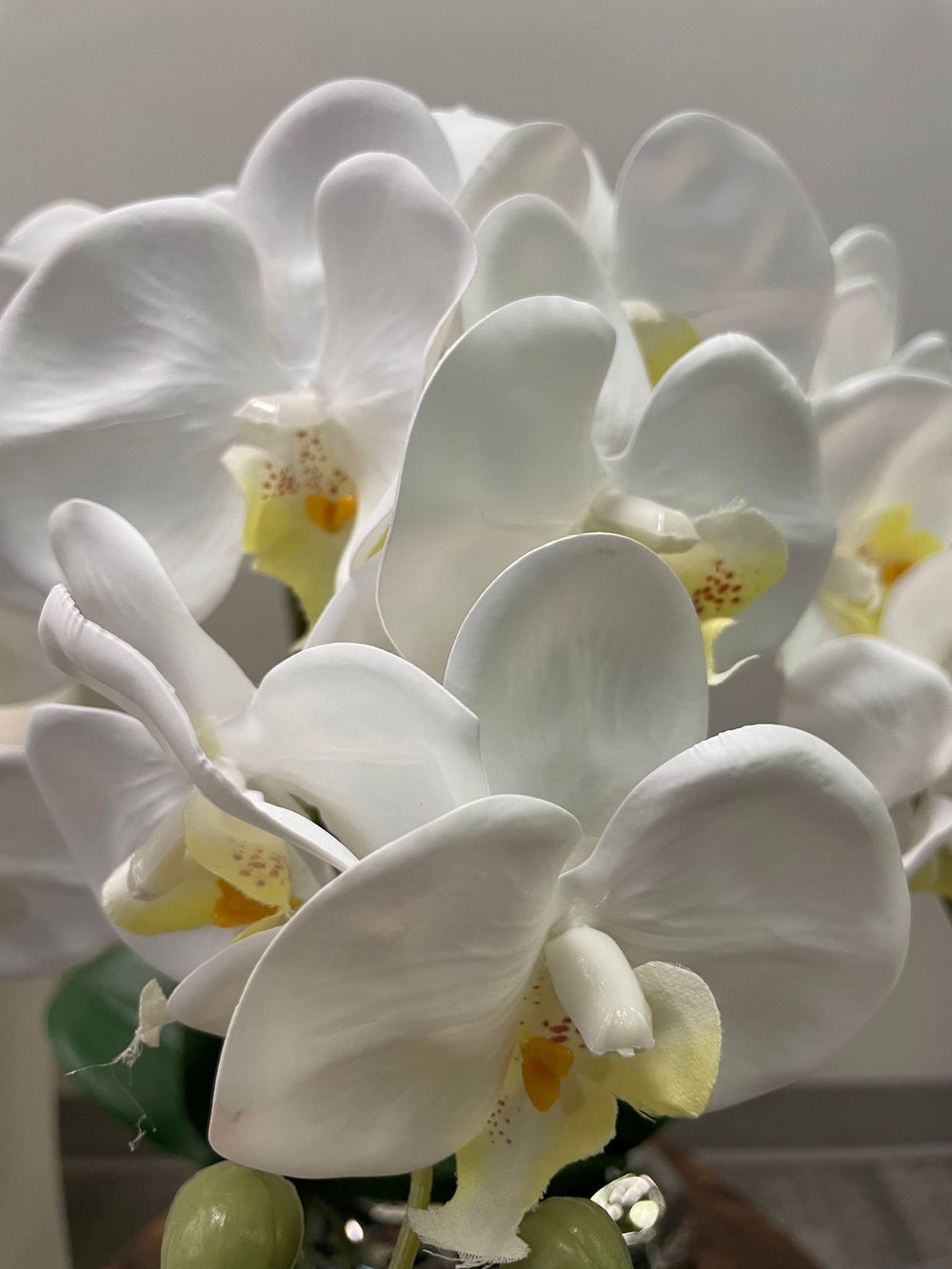 Close-up of white artificial orchid flowers showcasing their detailed petals and soft texture. Frequently asked question: How can I make artificial orchid flowers look more natural in my home decor?