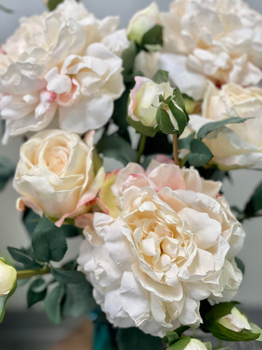 A close-up shot of artificial white and pale pink peonies, showcasing their soft petals and green leaves. Common question: Are artificial peonies a good alternative for real flowers in wedding decorations?