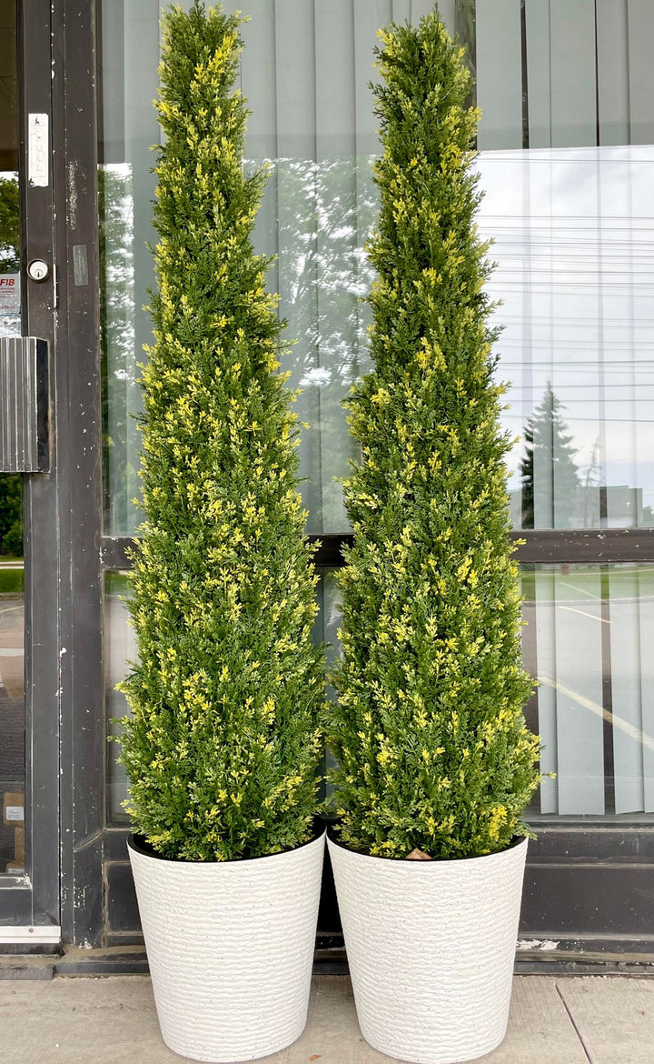Pair of artificial tall evergreen plants in matching white textured pots, featuring dense green foliage with yellow highlights, ideal for enhancing indoor or outdoor spaces.