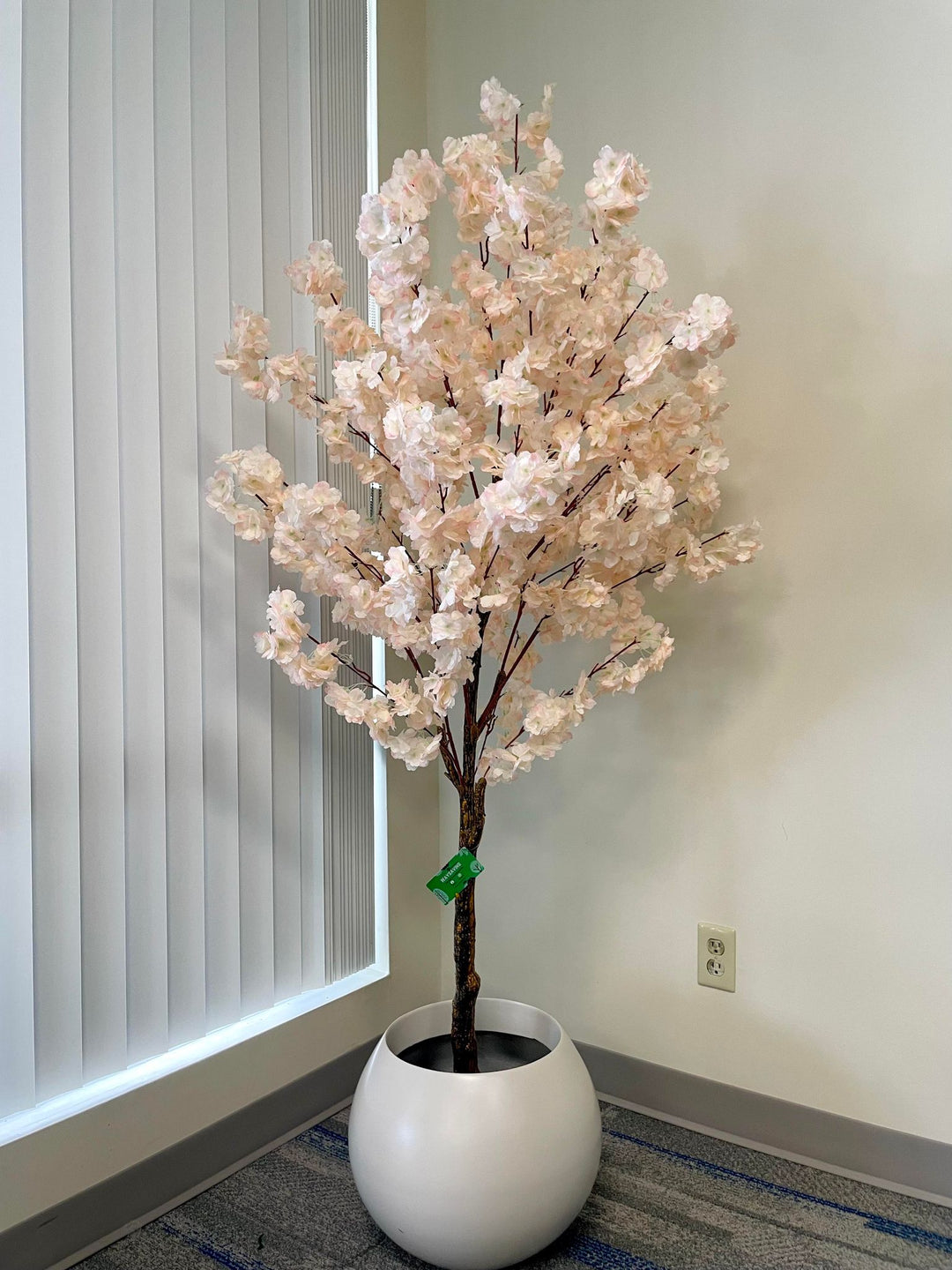 Artificial cherry blossom tree in a minimalist white planter, perfect for brightening up any indoor space with its delicate pink flowers