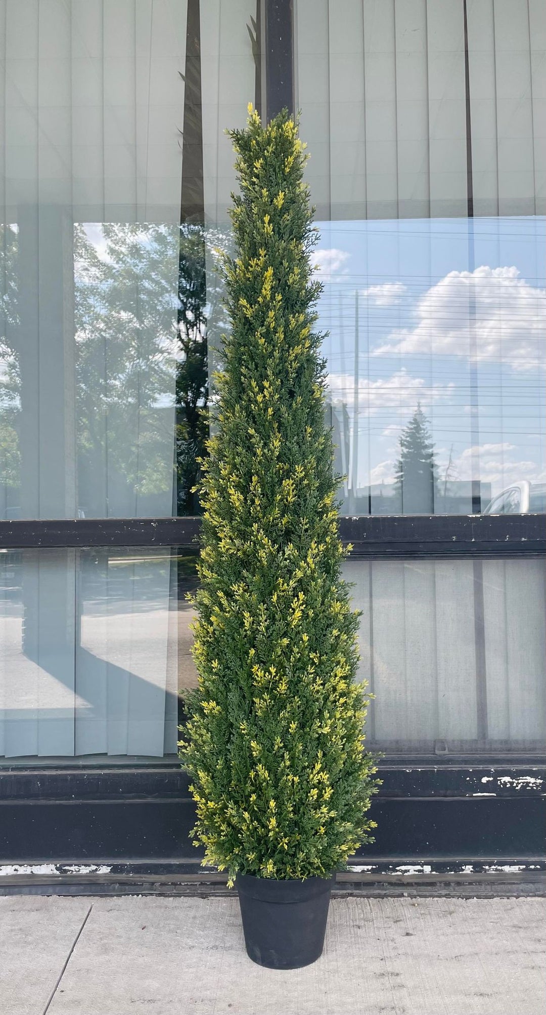 Artificial tall evergreen plant in a black pot, featuring lush green foliage with subtle yellow accents, perfect for outdoor or indoor decor