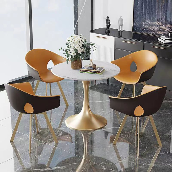What material is best for a modern dining table? Image of a round marble dining table with a gold base and four stylish, mid-century modern chairs featuring leather upholstery, placed in a sleek, contemporary dining room with marble flooring.