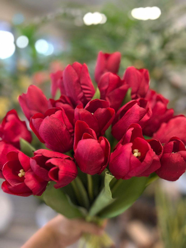 A vibrant bouquet of artificial pink tulips held by hand, with realistic petals and leaves. What are the best tips for choosing high-quality artificial flowers?