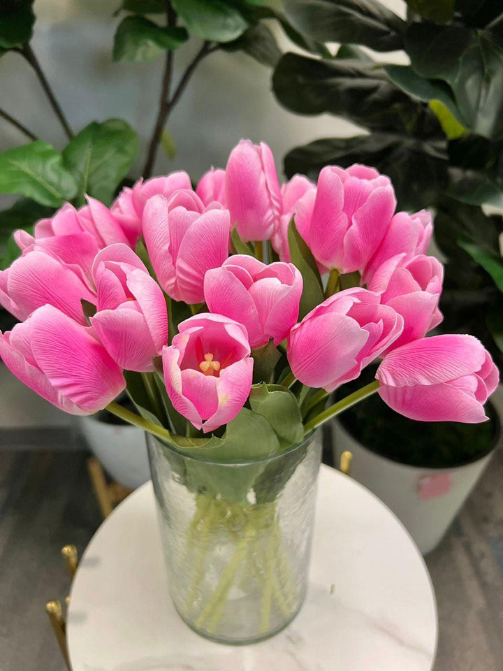 A vibrant bouquet of artificial pink tulips held by hand, with realistic petals and leaves. What are the best tips for choosing high-quality artificial flowers?