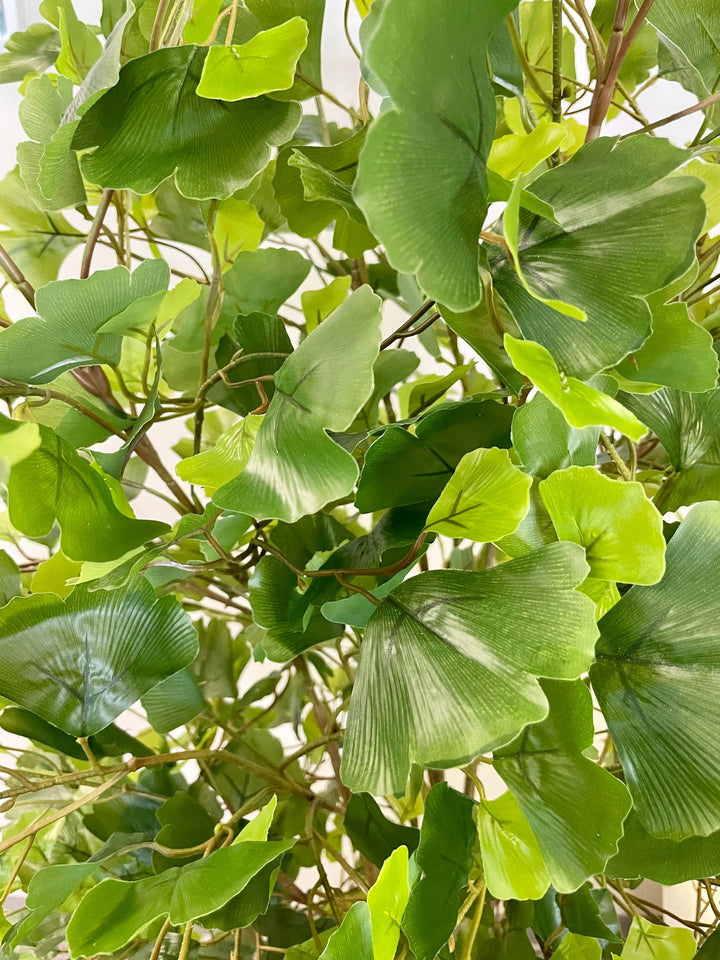 Close-up view of artificial green ginkgo leaves with lifelike texture and various shades of green, creating a natural and vibrant look for indoor decor.