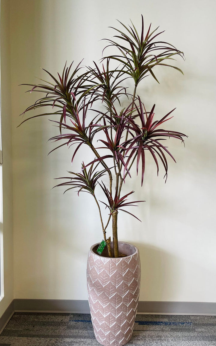 Artificial Dracaena plant with vibrant red-tinted leaves in a decorative pink geometric-patterned planter. This modern faux plant adds a touch of color and elegance to interior spaces, perfect for enhancing home or office decor.