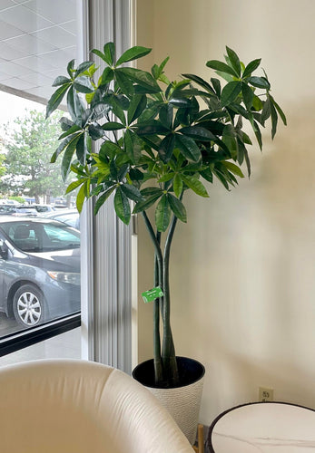 Artificial money tree with lush green leaves in a stylish white textured planter, placed beside a cozy white armchair in a modern indoor setting, perfect for enhancing office or home decor