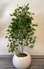 Load image into Gallery viewer, Artificial plant with lush green leaves placed in a modern white round pot, set against a neutral wall in an indoor setting
