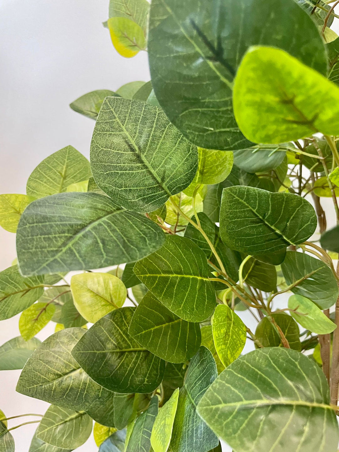 Detailed close-up of artificial green leaves with realistic veining and varying shades, showing a natural and vibrant appearance, perfect for indoor decor
