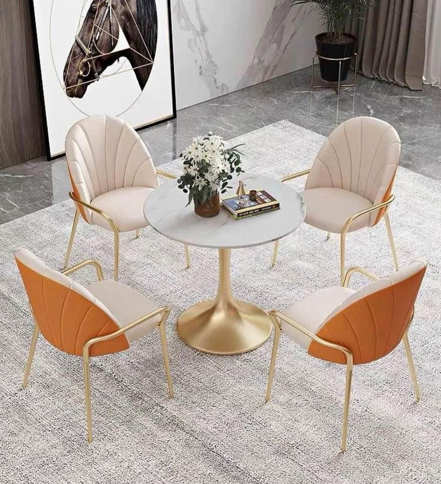 What is the best table shape for small spaces? Image of a round marble dining table with a golden base and four cushioned chairs, set on a neutral-colored rug in a modern dining room.