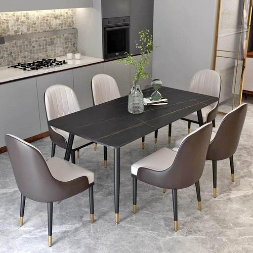 What is the best modern dining table for a compact kitchen? This elegant dining setup features a sleek black table with gold-accented legs, surrounded by six upholstered chairs in gray and white tones. The minimalist design fits perfectly in a modern kitchen space, creating a stylish and functional dining area.