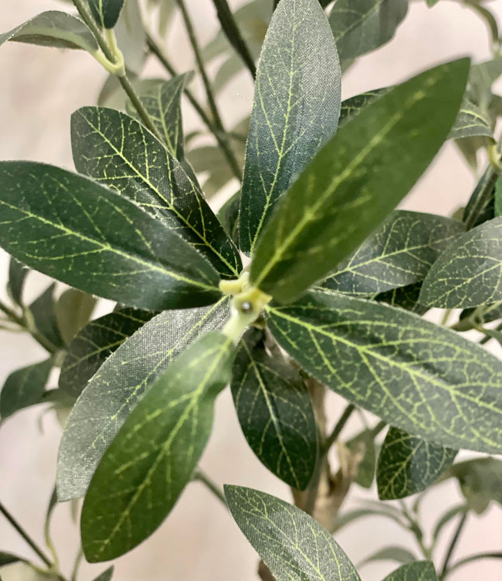 Close-up image of artificial olive tree leaves, highlighting the intricate vein patterns and realistic texture against a neutral backdrop.