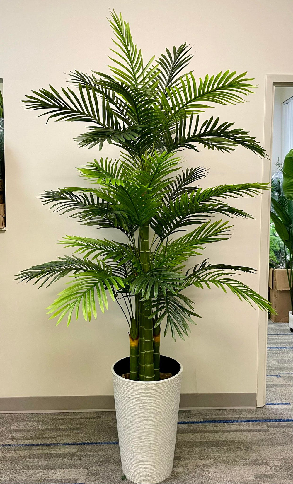 Large realistic artificial plant in a textured white planter, ideal for enhancing the decor of any indoor space with a touch of nature.