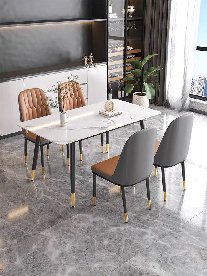 What chairs complement a modern marble dining table? This image features sleek tan leather chairs with black legs and gold accents, paired with a white marble dining table. The contemporary dining space includes minimalist shelving and subtle decor, creating a refined and elegant atmosphere.